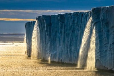 Melting Ice Shelf Waterfalls at Sunset