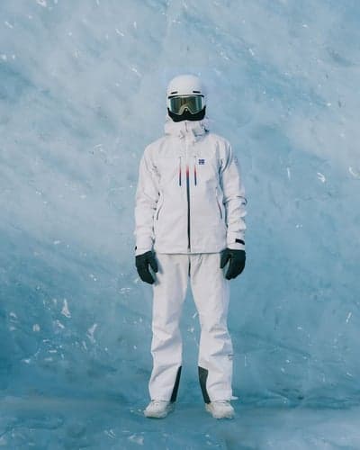 Skier in White Gear Against Blue Glacial Ice